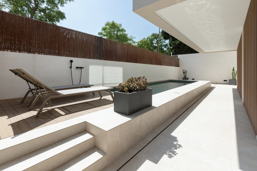 Piscina comunitaria con ducha exterior y tumbonas
