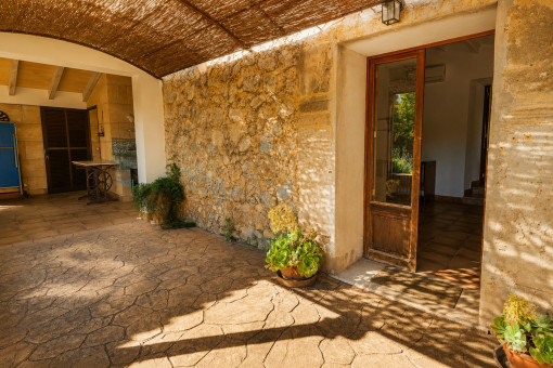 Patio cubierto con pared de piedra y plantas