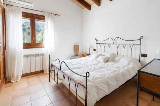 Dormitorio luminoso con cama de hierro forjado