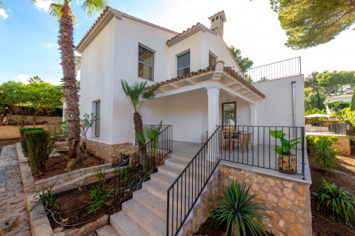 Vista trasera de la casa con terraza cubierta y acceso al jardín