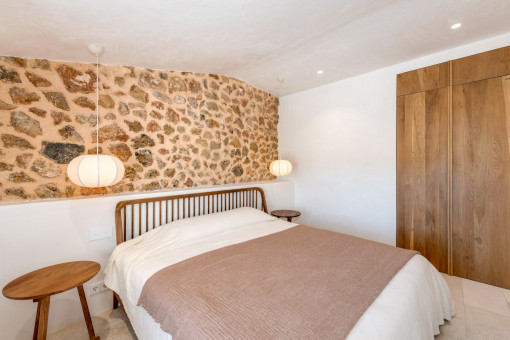 Dormitorio de invitados con pared de piedra y luz cálida