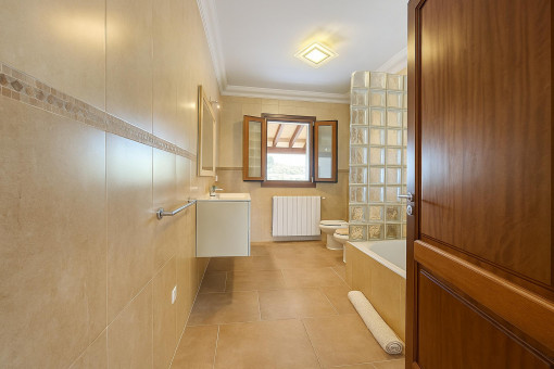 Amplio baño con bañera, luz natural y azulejos de buen gusto.