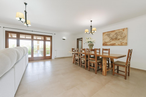 Comedor amplio con gran mesa de madera y acceso a la terraza cubierta.