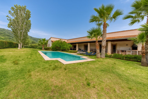 Jardín amplio con piscina y palmeras