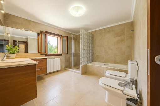 Baño elegante con bañera, bidé y luz natural en finca rústica cerca de Alcúdia