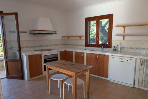 Cocina espaciosa con muebles de madera, electrodomésticos y acceso al jardín