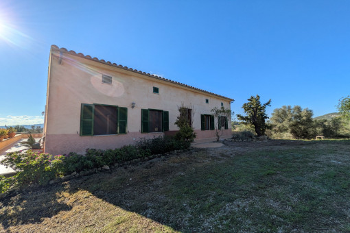 Vista exterior de la finca con zona ajardinada bien cuidada y elementos tradicionales mallorquines