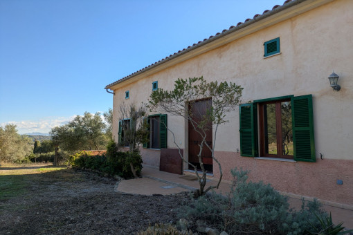 Vista exterior de la finca con zona ajardinada bien cuidada y elementos tradicionales mallorquines