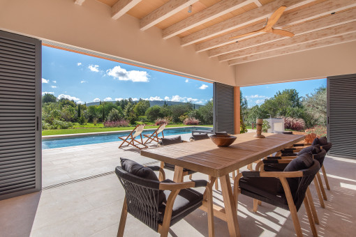 Comedor interior-exterior con vistas a un jardín mediterráneo frondoso