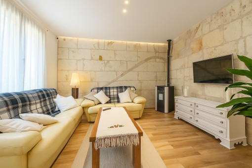 Salón con pared de piedra natural y estufa de pellets