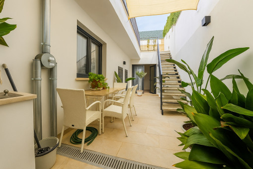 Patio en la planta baja con zona de comedor y escaleras hacia la piscina
