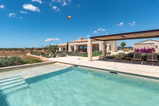 Elegante pérgola junto a la piscina con cómodas tumbonas