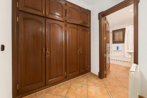 Pasillo con armario de madera y vista al baño