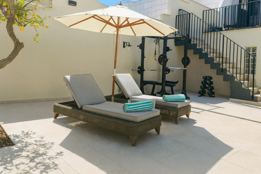 Sunny outdoor patio with loungers and gym