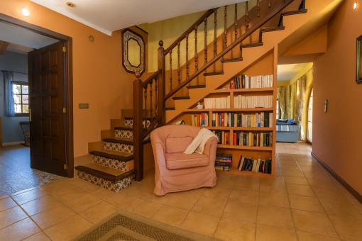 Acogedor recibidor con escalera y estantería