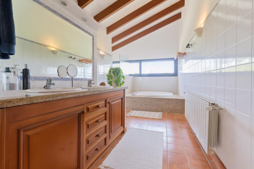 Baño luminoso con bañera y armario de madera